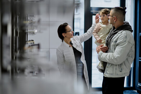 female optician consulting a man and little girl in an optical storer 