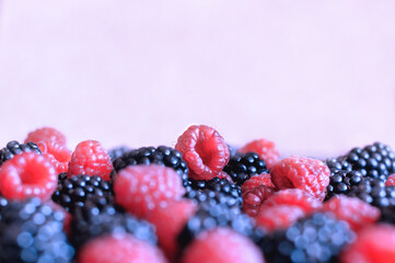 Assorted fresh raspberries and blackberries in the foreground with copy space on top. Selective focus with shallow depth of field