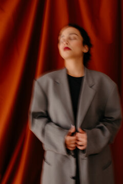 Blurred female in elegant jacket standing in studio