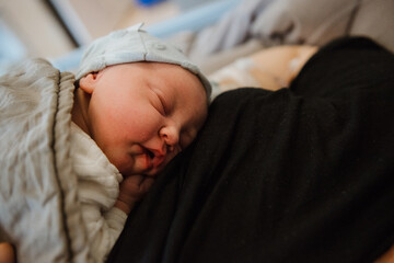 Sleeping newborn cuddled with mom