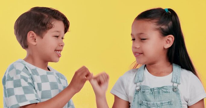 Happy children, hands together and trust with pinky promise for secret, agreement or deal in studio on a yellow background. Young kids or best friends with finger, swear or honesty for friendship