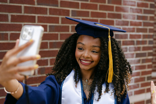  smiling college graduate taking a selfie 