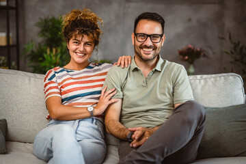Portrait of adult couple wife and husband hug and sit on sofa at home