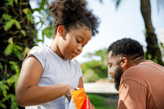 Cute girl eating snack by father in park