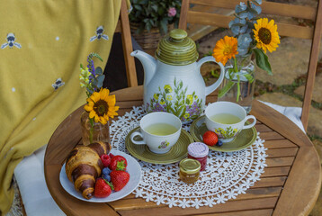 Morning summer tea with flowers and fruits on the veranda in the village house