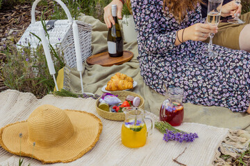 Summer picnic with wine and cheese in the lavender field, outdoors, sunset light