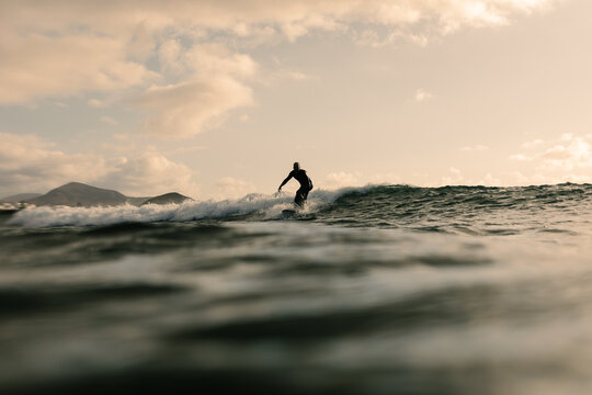 In the Atlantic Ocean a surfer expertly ride a wave during a sunset