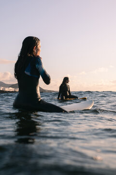 Professional surfers relax floating on their surfboards during sunset