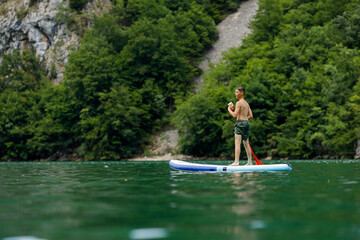 Naklejka premium Young boy on a stand up paddle