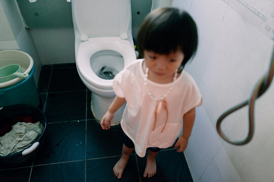 little girl threw the newspaper into the toilet