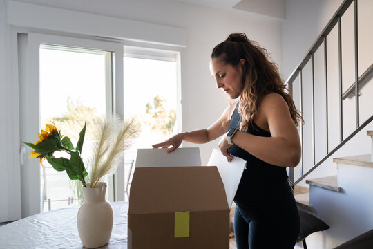 Woman unpacking cardboard box at home