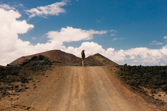 Woman can be seen in the distance, leisurely walking along a dirt road