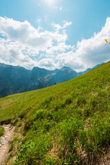 Paraglider with Backpack Walking Up the Hillside in the Mountain Landscape