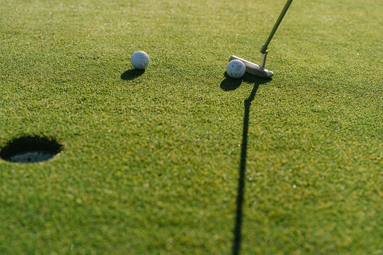 golf club aiming to get ball in a hole . 