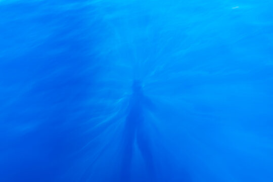 Deep blue of the ocean with the shadow of a person.