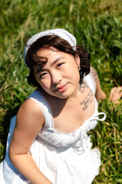 Portrait of alluring woman sitting on grass 