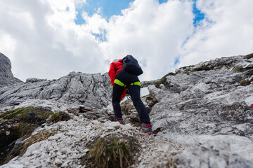 Hiker with Backpack Walking up a Rocky Mountain Trail