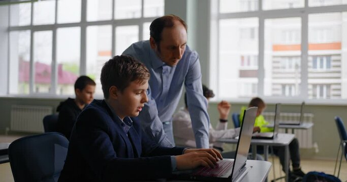 Teen Boy Consulting With Teacher In Classroom, Future Programmer Studying In School