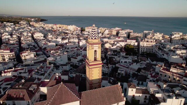 Coastal city aerial view with historic bell tower, white rooftops, and Mediterranean architecture