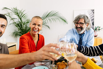Happy group of multi generational family toasting wine while enjoying lunch at home