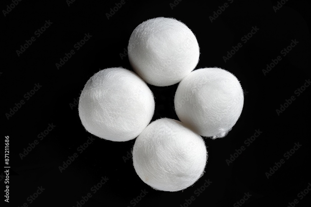 Poster close-up of four small white wool balls lying on a black surface, great for abstract or textile desi