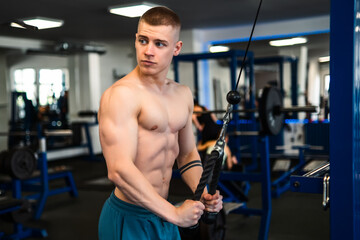 Naklejka premium A young man works out on a cable machine in a gym