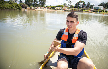 young man in life jacket rowing a small boat on a lake