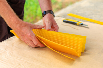 Sliced beeswax blanks for the production of decorative candles in the male hands of farmer
