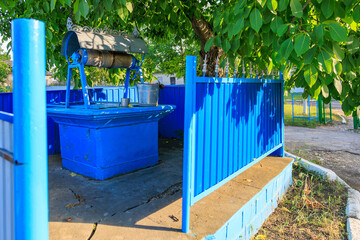 A blue water fountain sits in front of blue fence