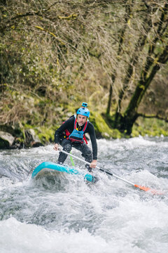 Sportive paddler surfing with paddleboard in splashing white river