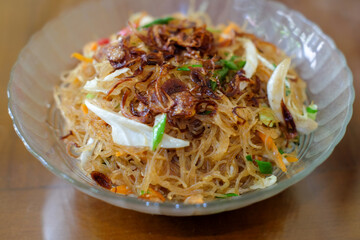 Fried rice vermicelli mixed with cabbage and carrots sprinkled with fried onions, served in a bowl. A famous spicy street food menu in Asia, oriental food, chinese food.