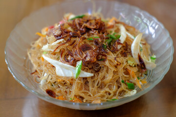 Fried rice vermicelli mixed with cabbage and carrots sprinkled with fried onions, served in a bowl. A famous spicy street food menu in Asia, oriental food, chinese food.