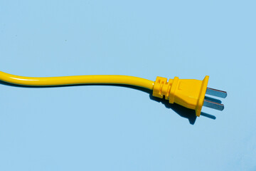 Yellow electric power cable with plug on blue background.
