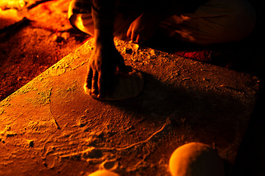 Bedouin people kneading bread by fireplace, traditional method
