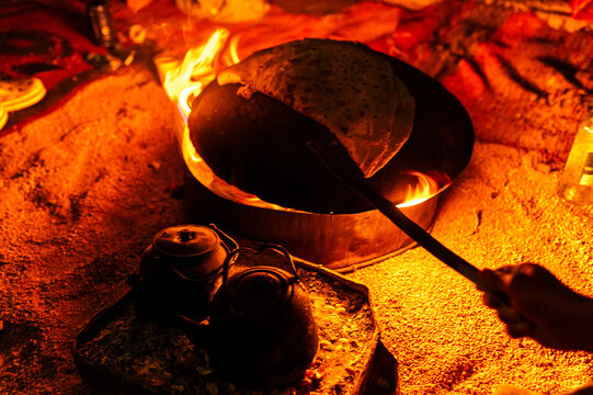 Bread baking over campfire at night, traditional cooking