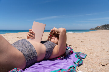 Woman relaxing with book on sunny beach
