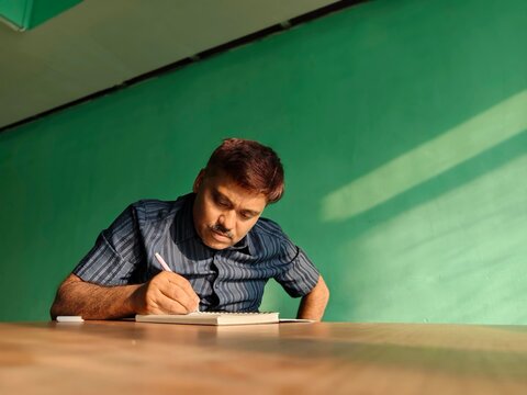 Middle aged Indian man wring inside a house