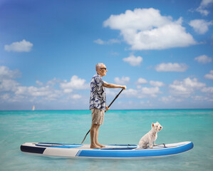 Elderly man in the sea standing on a paddling board