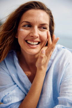 Happy woman applies cream to her face