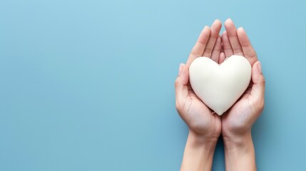 Photograph of hands gently holding a white heart-shaped object with a blue backdrop, symbolizing purity, love, and care in a minimalistic and contemporary style.