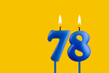 Blue birthday candle on yellow background - Number 78