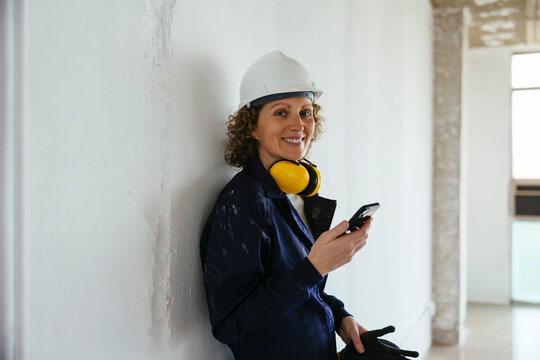 Smiling construction worker on site with smartphone