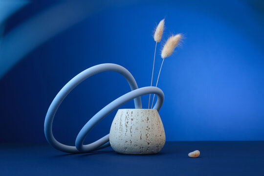 Abstract still life with ceramic vase and dry flowers on blue backdrop
