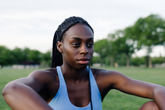 Empowered Afro-European woman exudes confidence sitting on the grass