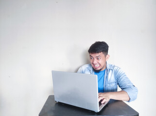 A man on his working place looking to laptop with shocked expression