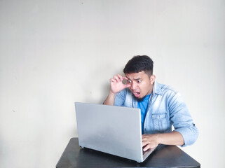 A man on his working place looking to laptop with shocked expression