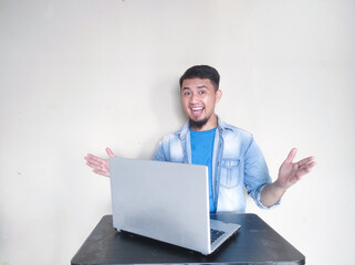 Asian mature man smiling confidently looking at the camera while working in front of his laptop