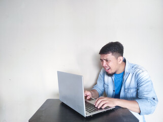A man on his working place looking to laptop with shocked expression