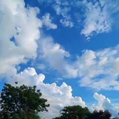 Obraz premium Bright blue sky with fluffy white clouds forming over a green tree line
