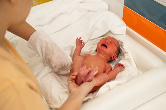 A newborn baby crying while taking his first bath in a hospital